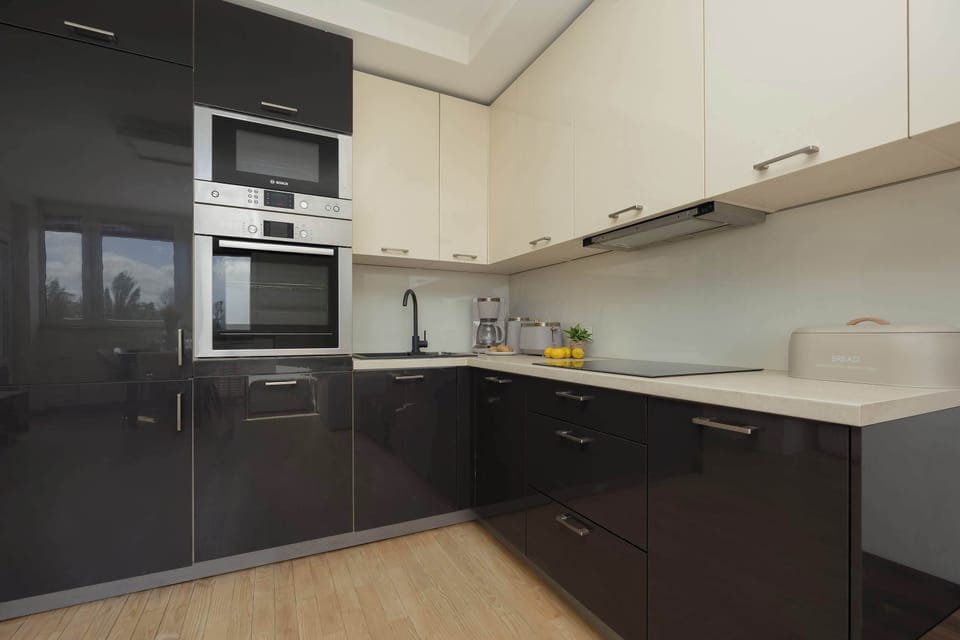 A sleek kitchenette area with dark cabinetry and built-in appliances, including an oven and microwave. The contrast between dark fronts and light countertops gives it a contemporary look.