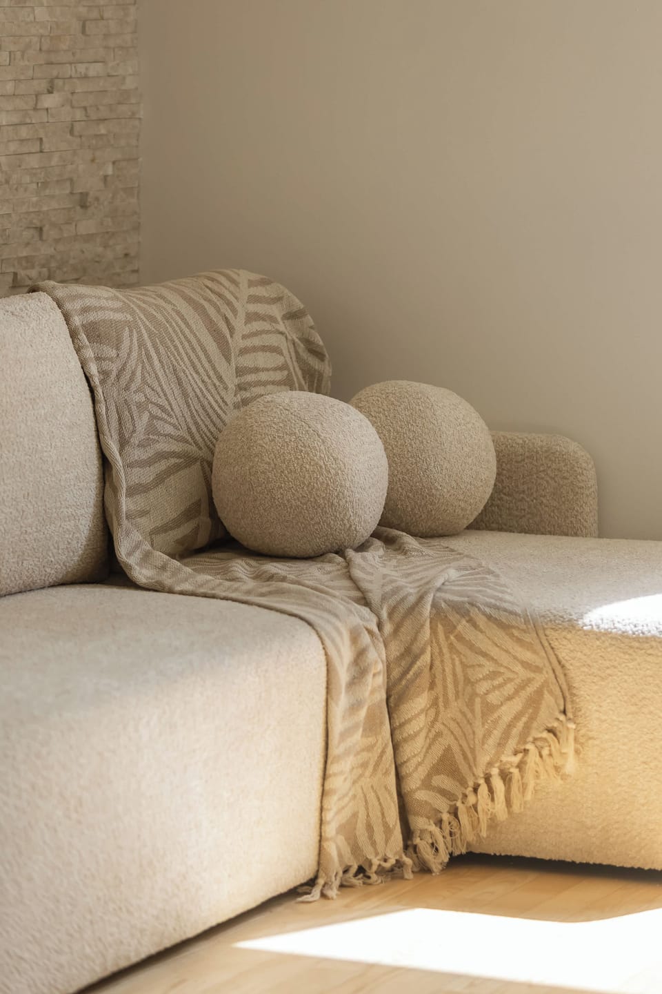 A soft, neutral-toned close-up of a bed with decorative pillows. The textures and colors create a warm and comfortable atmosphere.