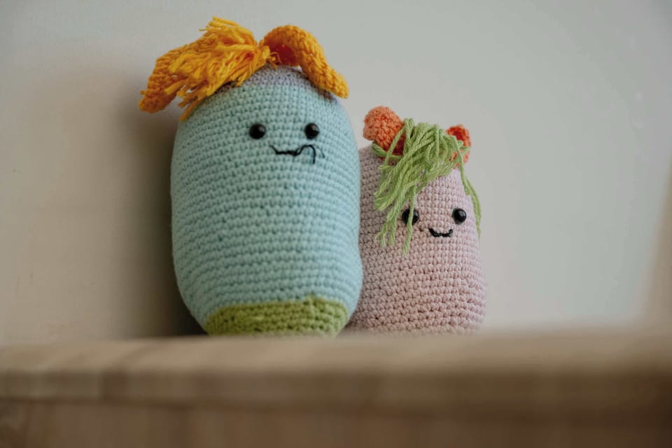 Two small knitted decorative figures placed on a shelf, bringing a playful and warm accent to the space. The soft textures make the interior feel more inviting.