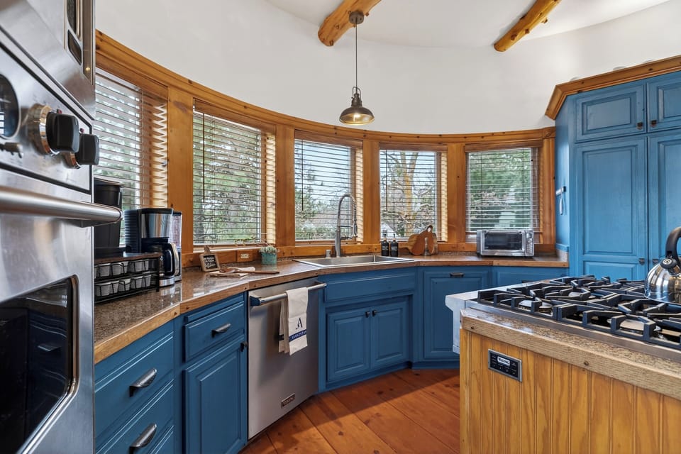 Warm log‑beam kitchen with blue cabinetry, a wood‑top island, and cozy cabin character throughout.