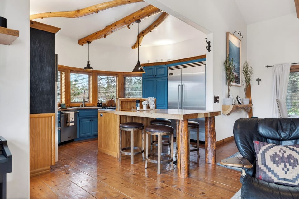 Warm log‑beam kitchen with blue cabinetry, a wood‑top island, and cozy cabin character throughout.