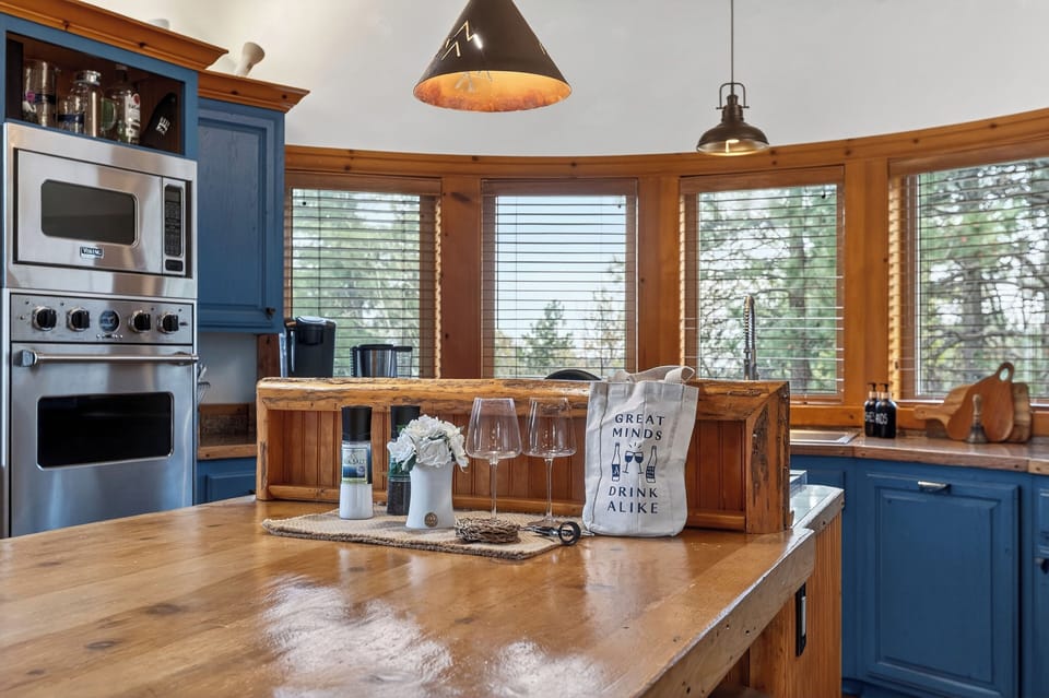 Warm log‑beam kitchen with blue cabinetry, a wood‑top island, and cozy cabin character throughout.