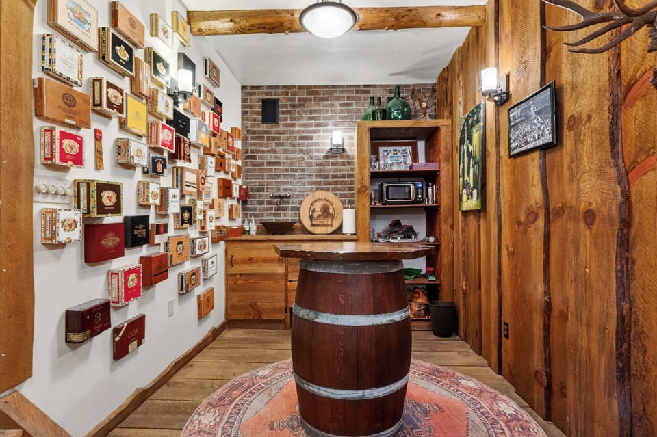 Cozy rustic bar with a brick backdrop, barrel table, and a unique wall of vintage cigar boxes.
