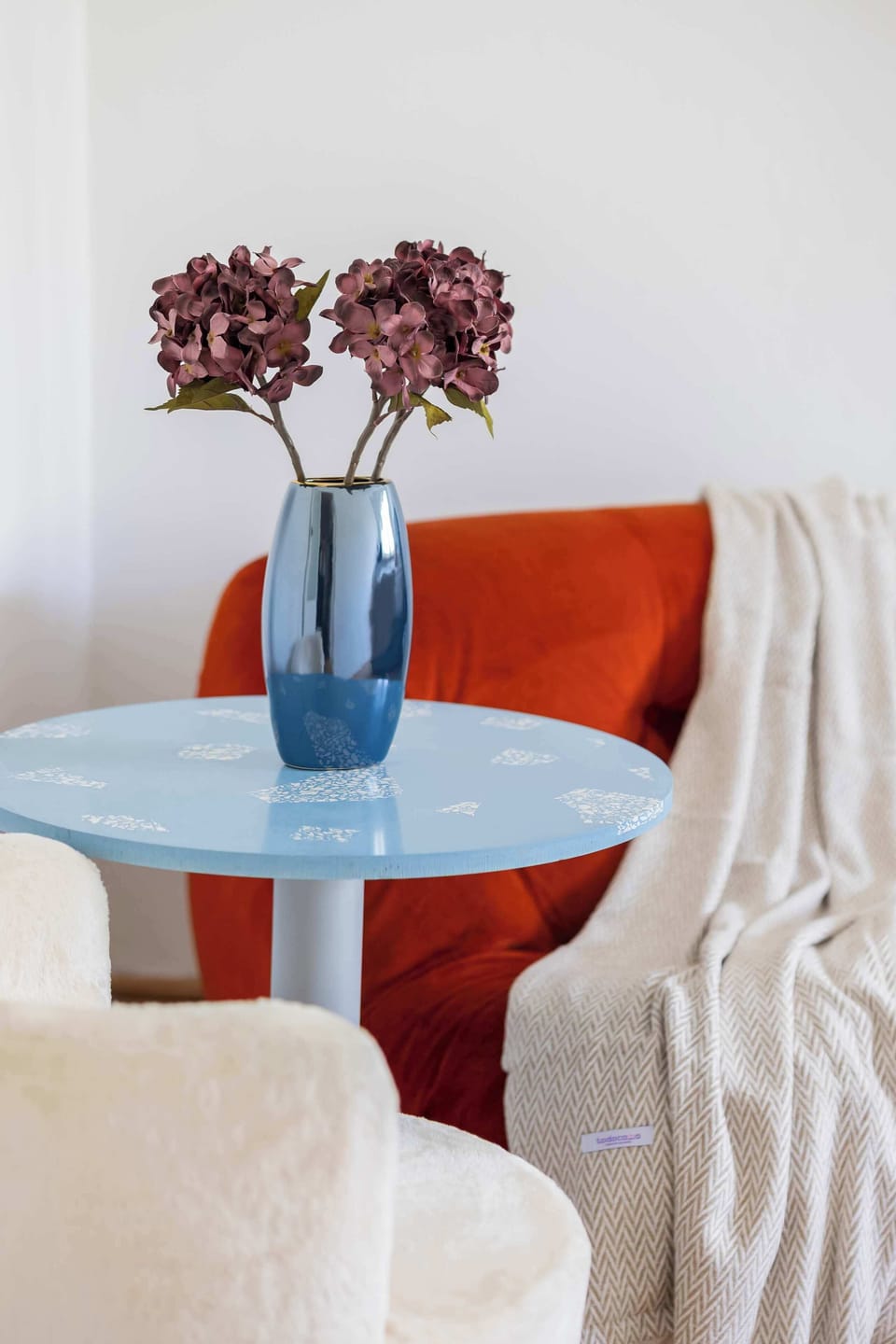 Bedroom with a round table, red chairs, and a vase with flowers. The space feels cozy and decorative.