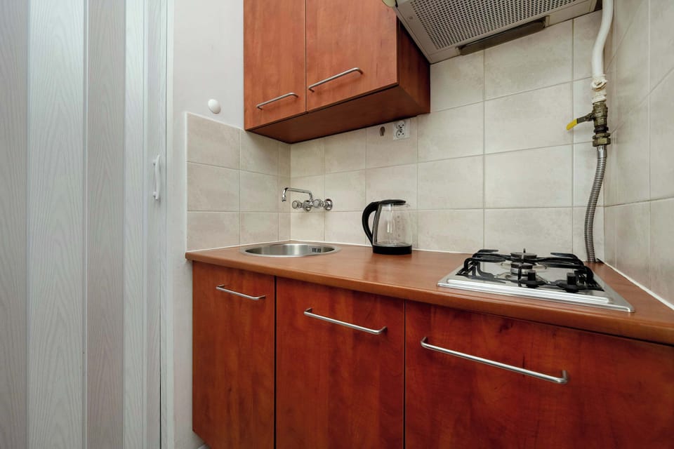 A compact kitchen with wooden cabinets, a stove, and countertop workspace. It is fully functional and designed for convenient cooking.