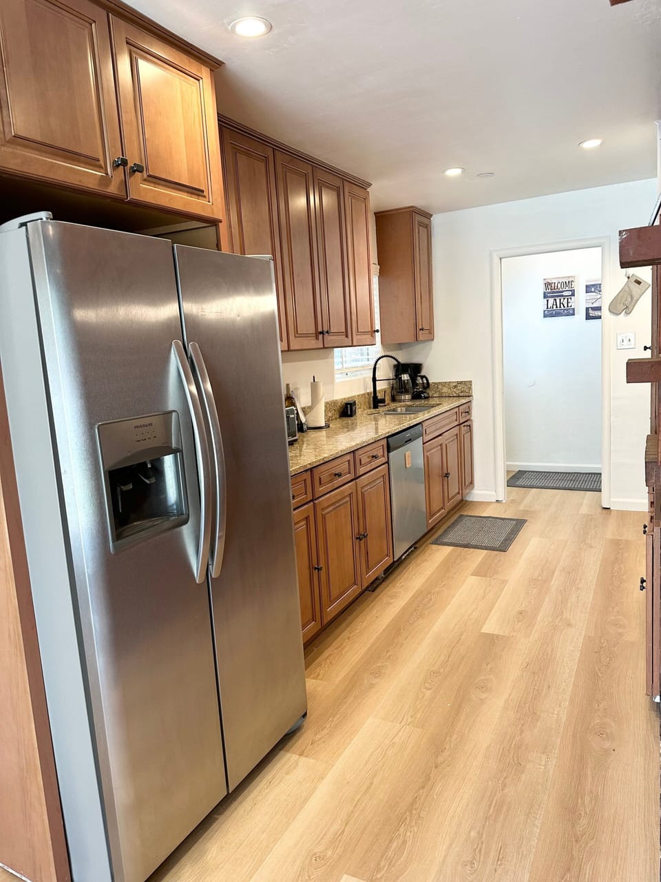 Kitchen with refrigerator, sink, dishwasher, coffee maker, cabinets, and doorway.