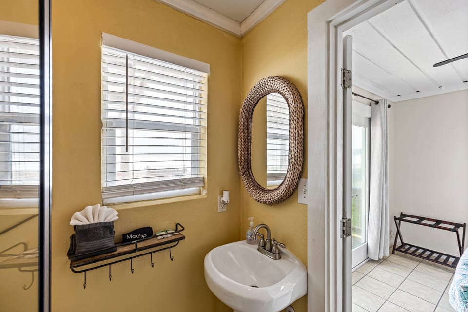 Bathroom vanity area with modern sink, mirror, and natural lighting for convenient guest use during your Galveston stay.