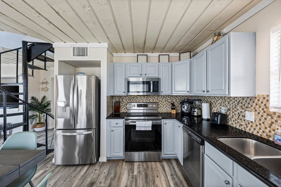 Fully equipped kitchen with stainless steel refrigerator, electric stove, microwave, and ample counter space for extended stays.
