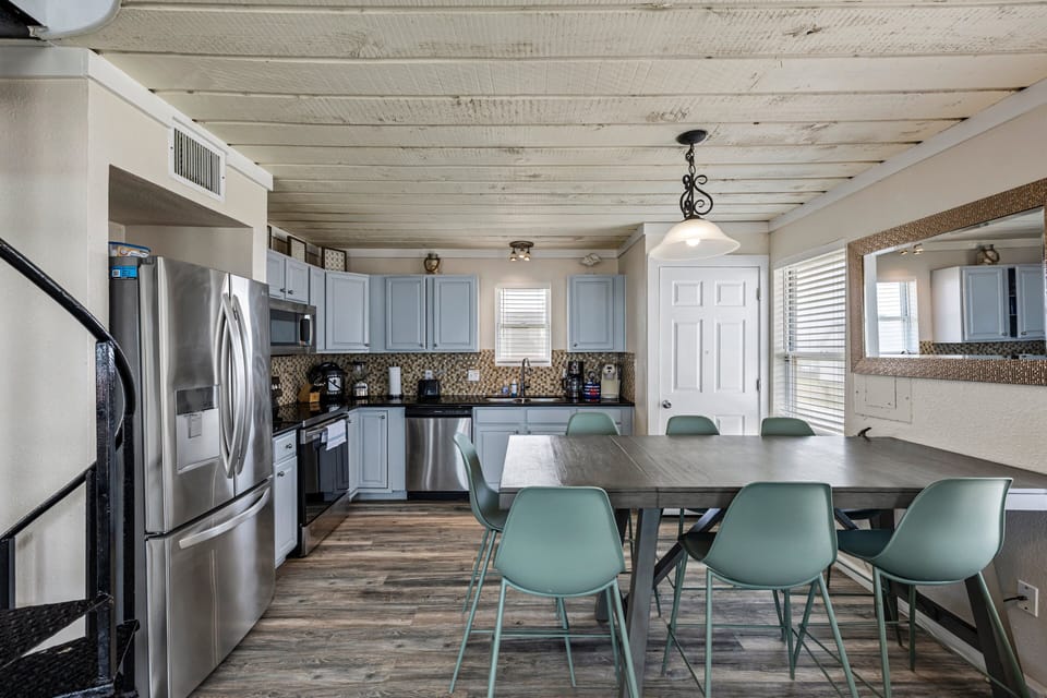 Coastal-style kitchen and dining area with stainless steel appliances, large island seating, and open layout designed for group beach vacations.