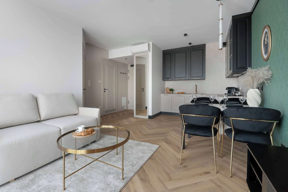 A bright living room offers a plush white sofa and a marble-topped coffee table resting on a soft, light-colored rug.