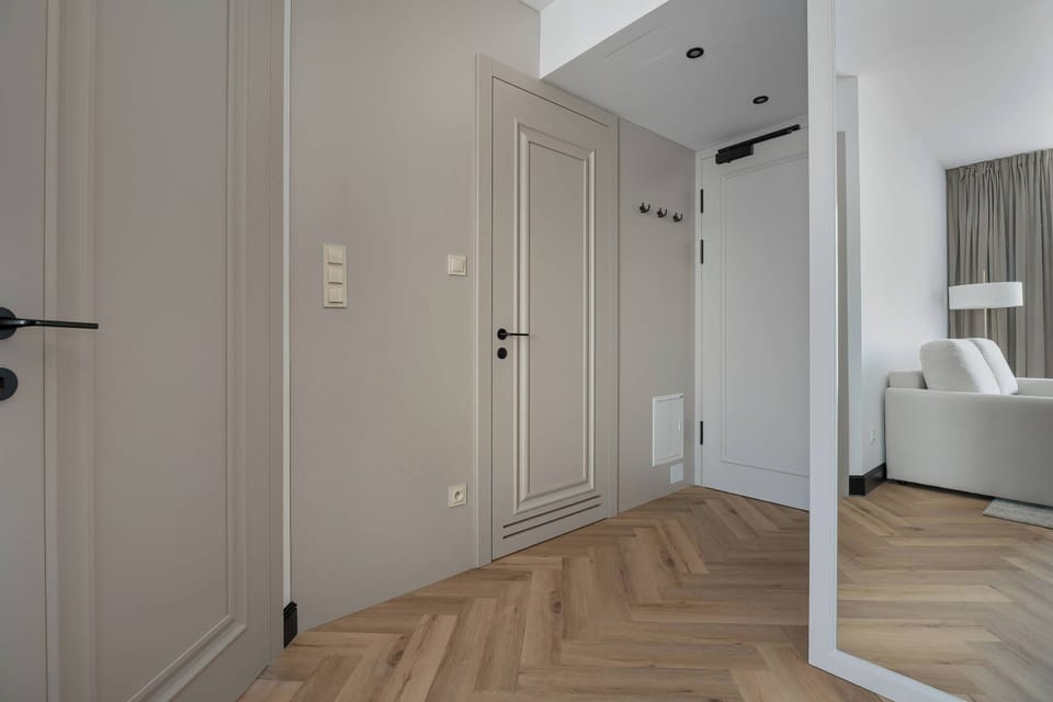 A minimalist hallway with light wooden doors leads into the bright, open-plan living area of the property.