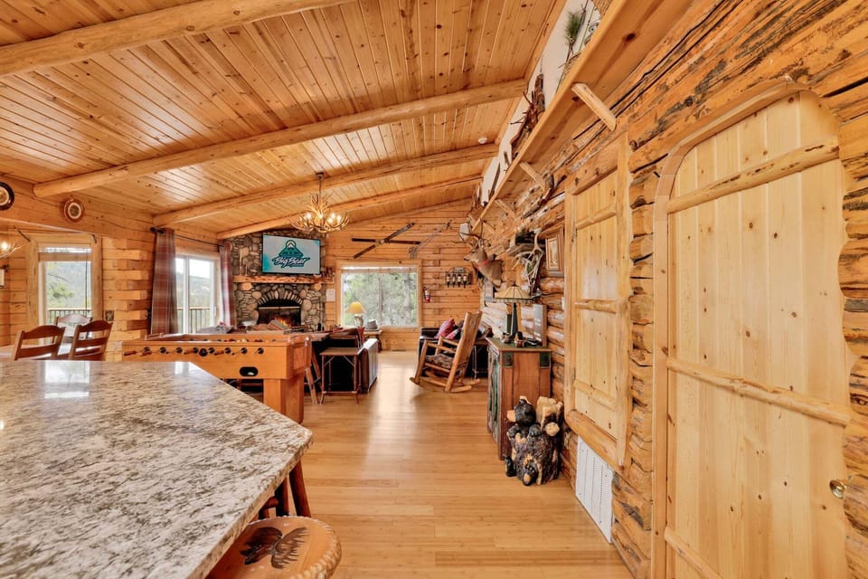 Soaring wood ceilings, a cozy stone fireplace, and a foosball table make this great room the heart of the cabin. Perfect for game nights, movie marathons, or just relaxing together.