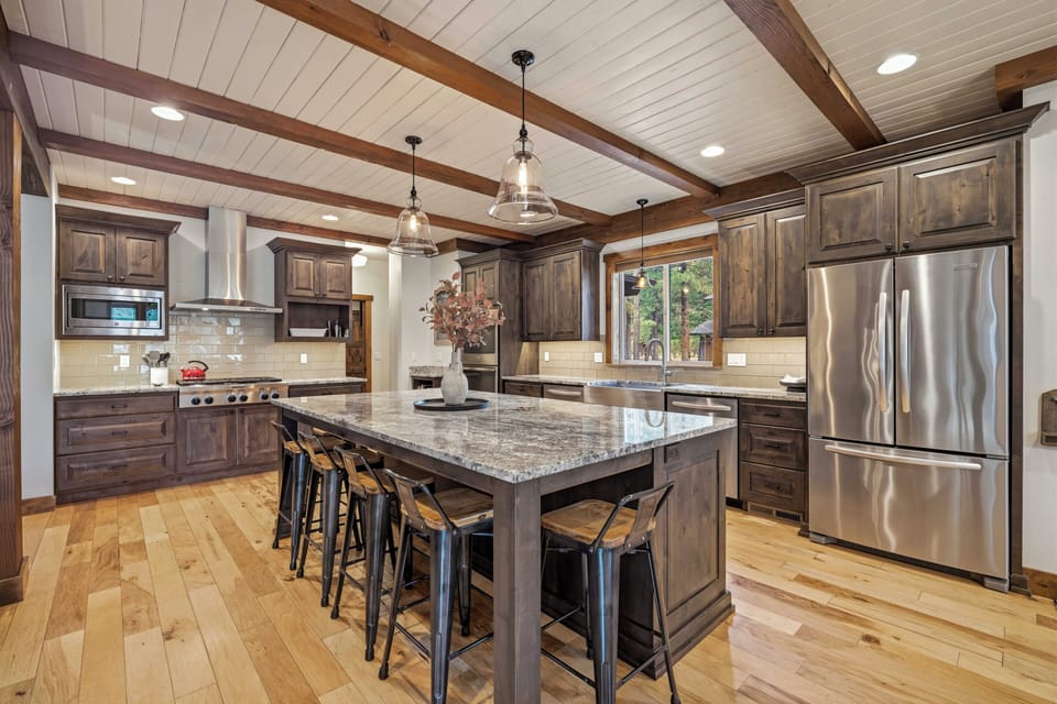 Step into your gourmet kitchen where rustic wood beams frame modern appliances, creating the perfect space for cooking memorable meals together.