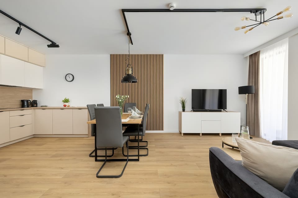 A wide-angle view of a bright living room connected to a kitchen and dining area.