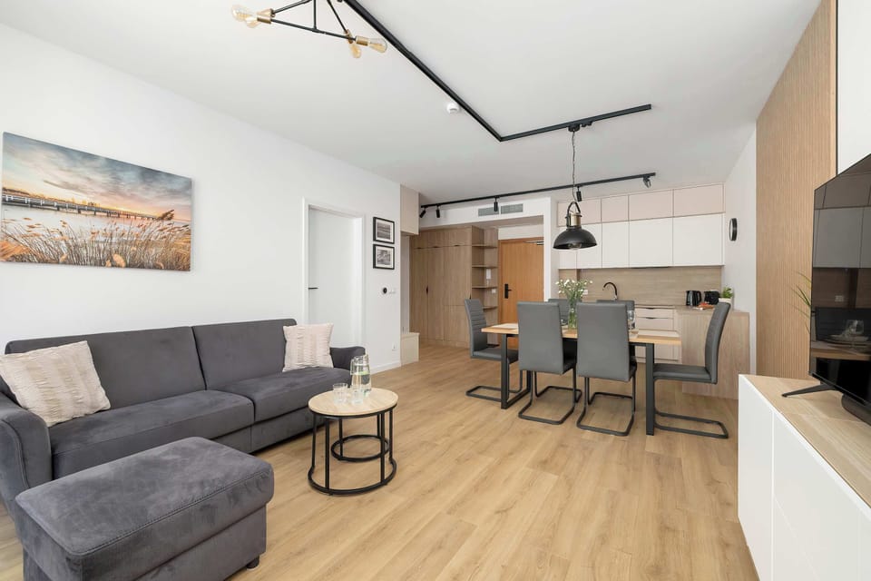 A cozy lounge corner with a sofa, coffee table, and TV set against a clean white wall.