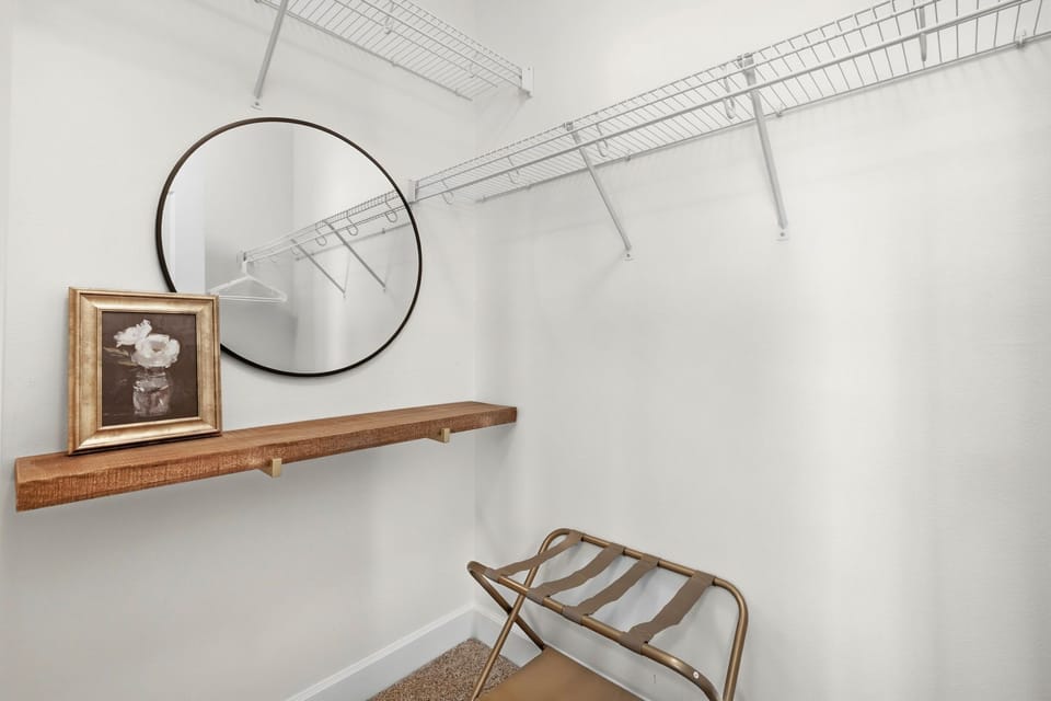 Walk-in closet offers organized shelving, a luggage rack, and a stylish mirror.