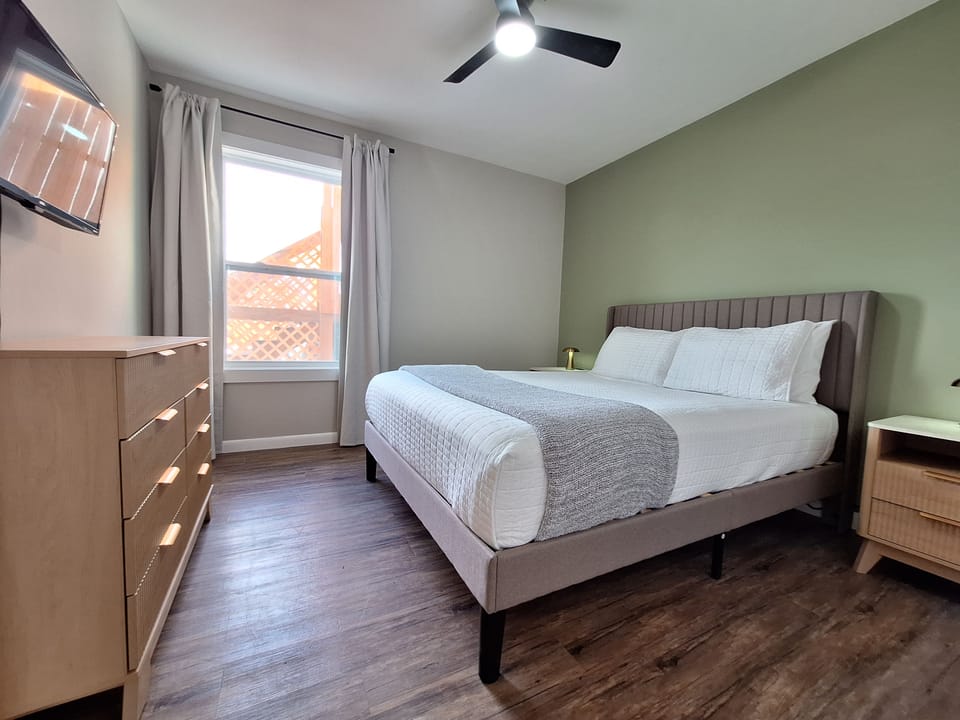 Bright, modern king bedroom with TV and stylish, calming decor
