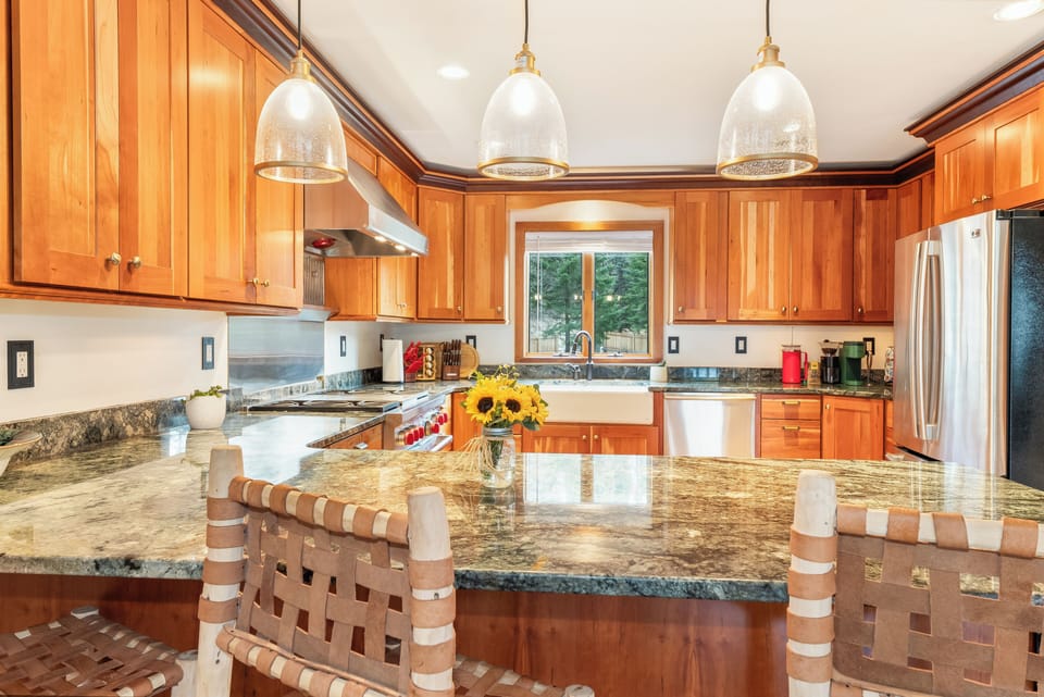 You'll love cooking in this stunning kitchen with granite counters, warm wood cabinets, and pendant lighting creating the perfect culinary space.