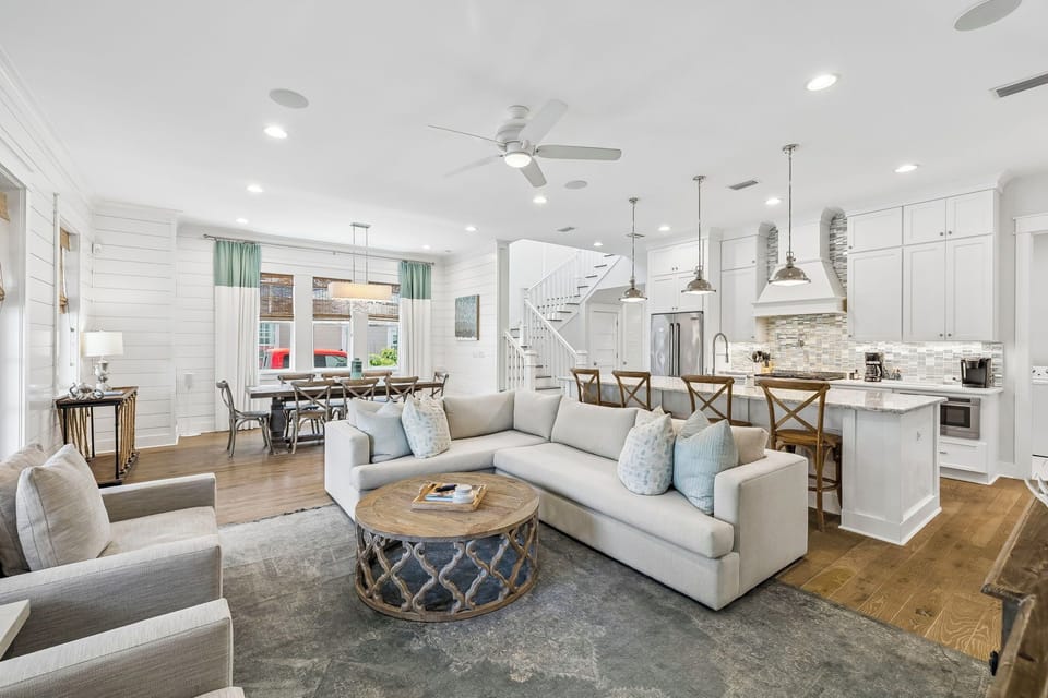 Settle into this bright, open living space where coastal charm meets modern comfort. Soft sofas and a welcoming kitchen island create a relaxed atmosphere for your memorable stay.