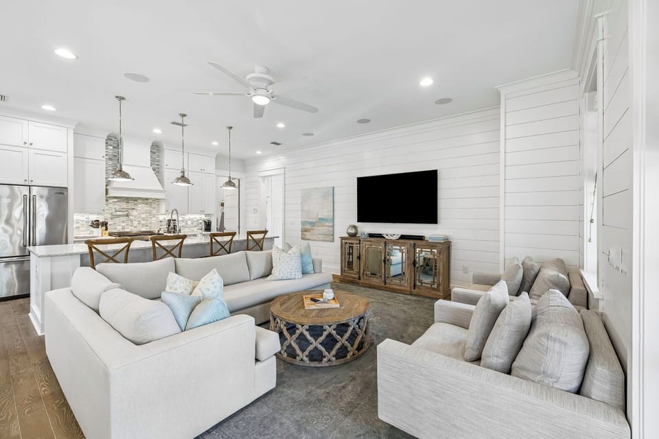 Sink into plush sofas in your bright, coastal living space with a fully equipped kitchen and shiplap accent wall—perfect for gathering after beach days or preparing meals together.