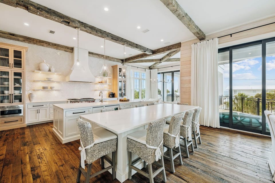 Cook and gather in this stunning kitchen featuring rustic beams, marble counters, and panoramic views through floor-to-ceiling windows.