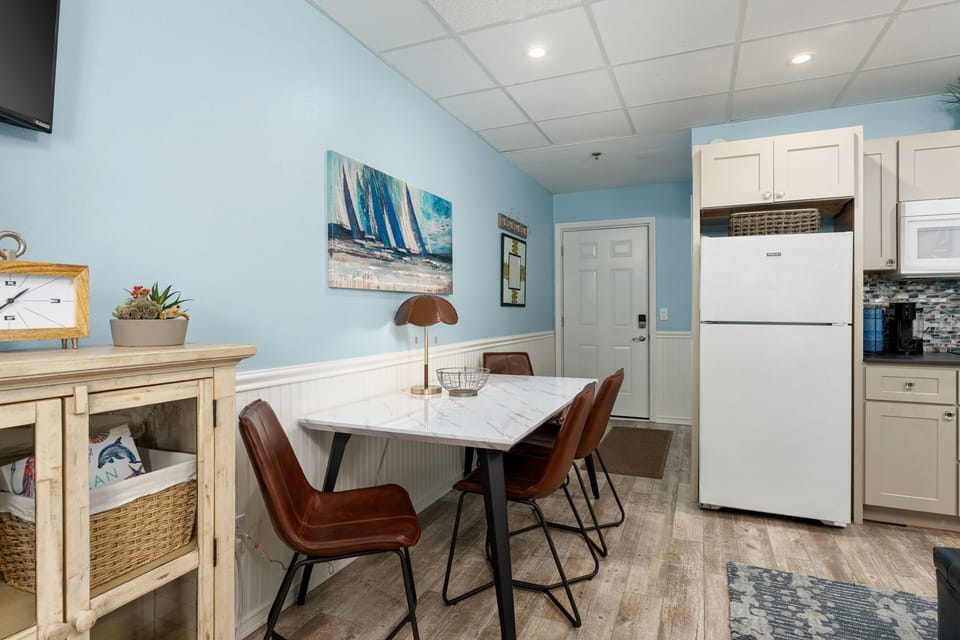 Gather around your stylish dining table for memorable meals in this coastal-themed kitchen with modern appliances and charming nautical touches.