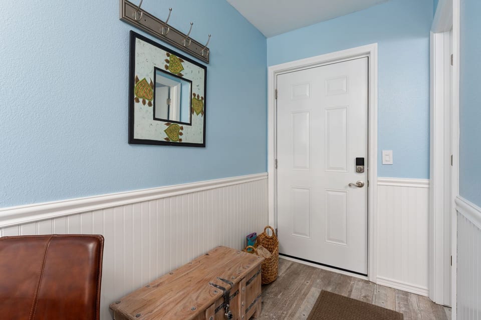 Your charming entryway welcomes you with coastal blue walls and thoughtful touches like hooks for your belongings and a cozy bench.