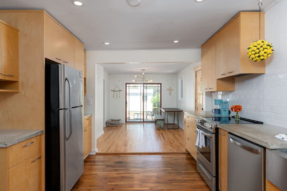 Your modern galley kitchen features warm wood cabinetry, stainless appliances, and flows seamlessly into your bright living space with patio access.