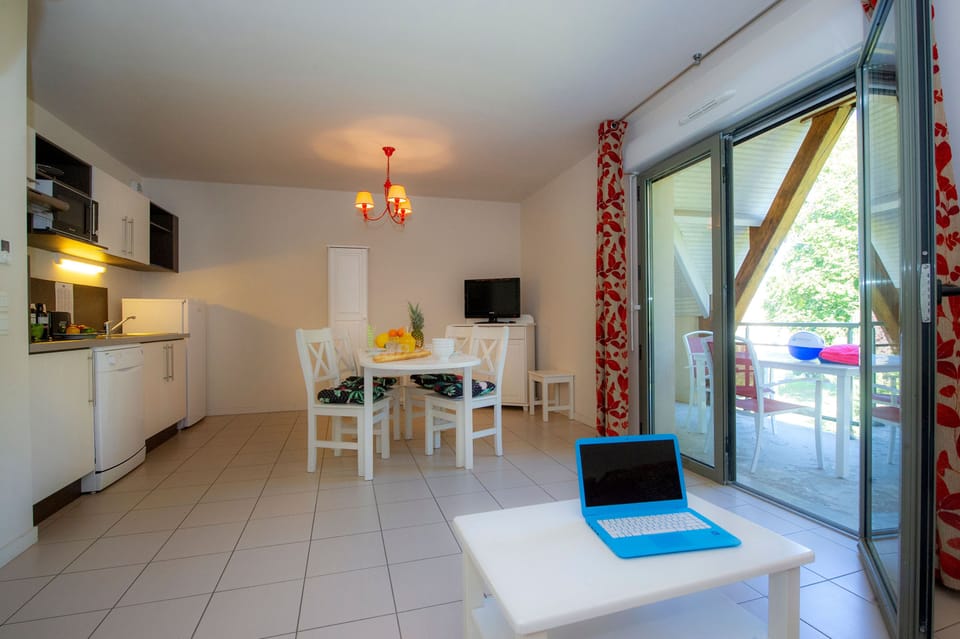 Round dining table and coffee table with balcony visible behind — the sliding doors bring the park greenery inside