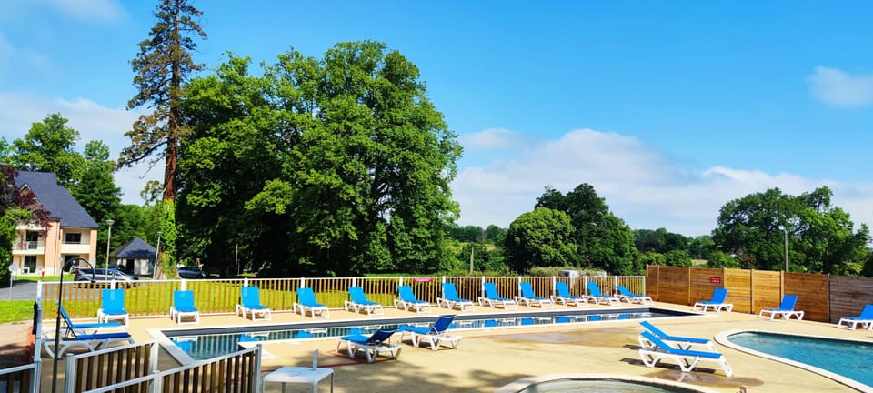 Sun loungers line the poolside, backed by the tall trees of the surrounding park.