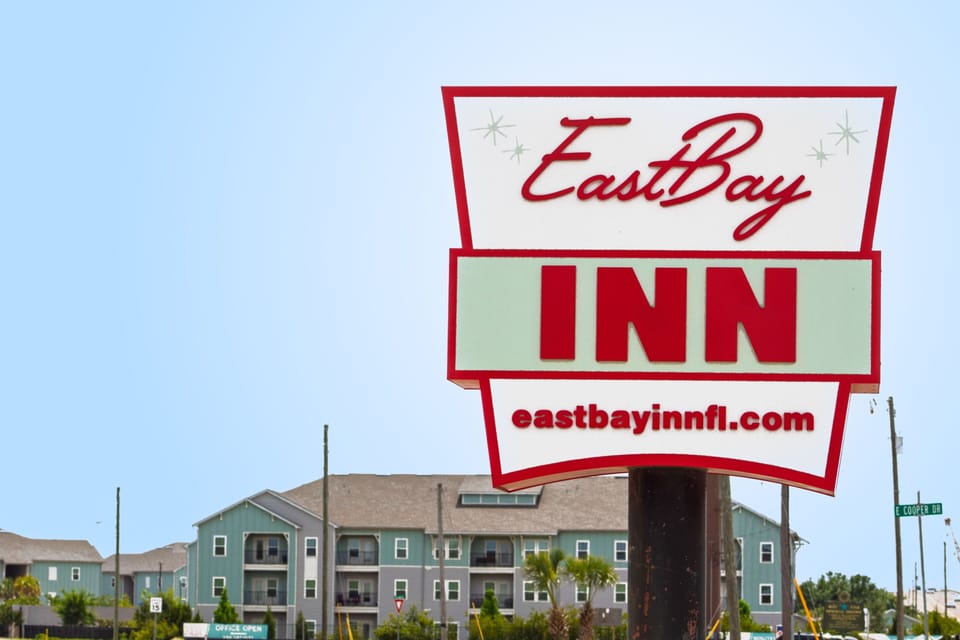 Exterior property entrance sign for East Bay Inn against a clear blue sky.