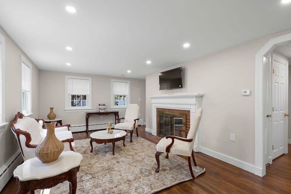 Living room featuring traditional armchairs, an area rug, and a fireplace with a TV.