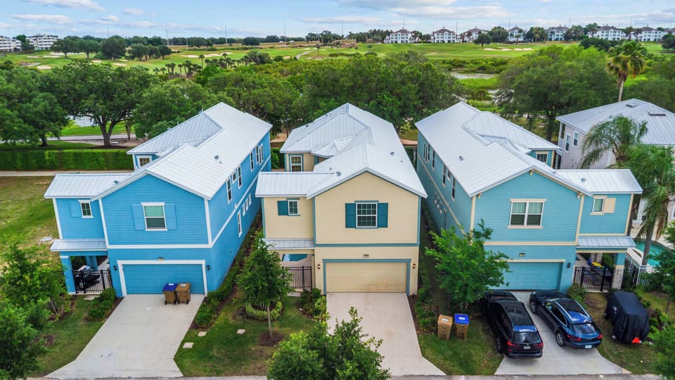 Colorful homes with metal roofs overlooking a golf course and lush greenery.