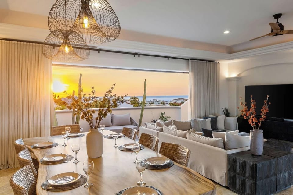 Open living and dining space with elegant furnishings and beautiful sunset views over the ocean.