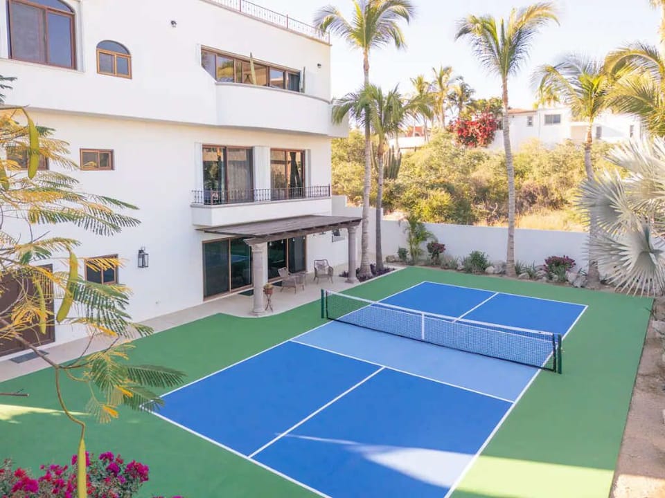 Private pickleball court located right on-site, surrounded by palm trees and lush tropical greenery for endless outdoor fun.