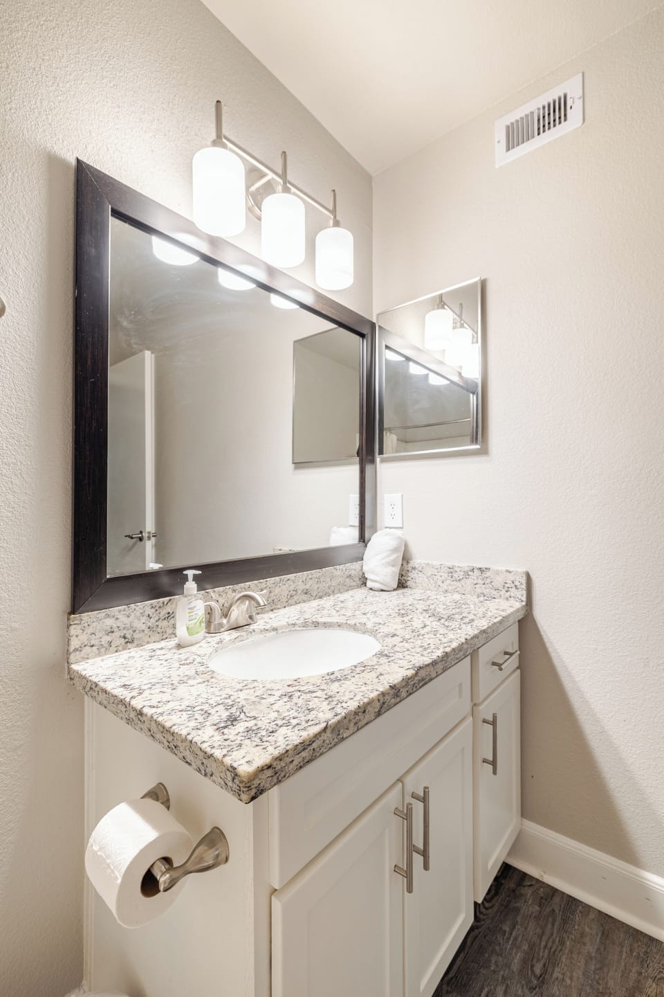 Bright bathroom vanity with granite counters and stylish modern lighting