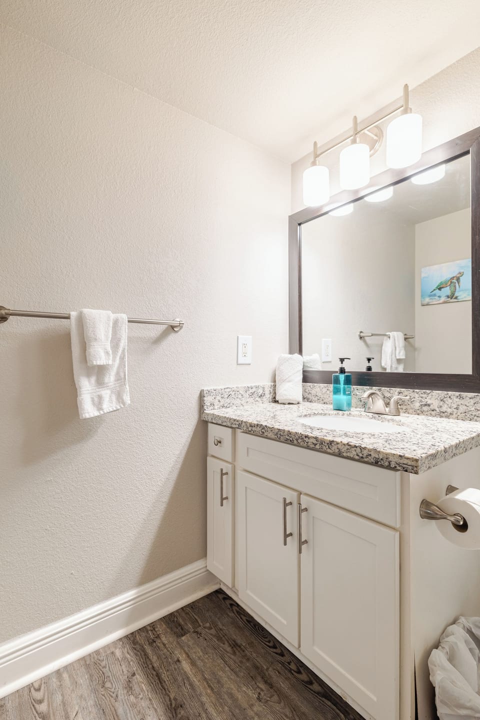 Bright updated bathroom with granite vanity, large mirror, and modern lighting