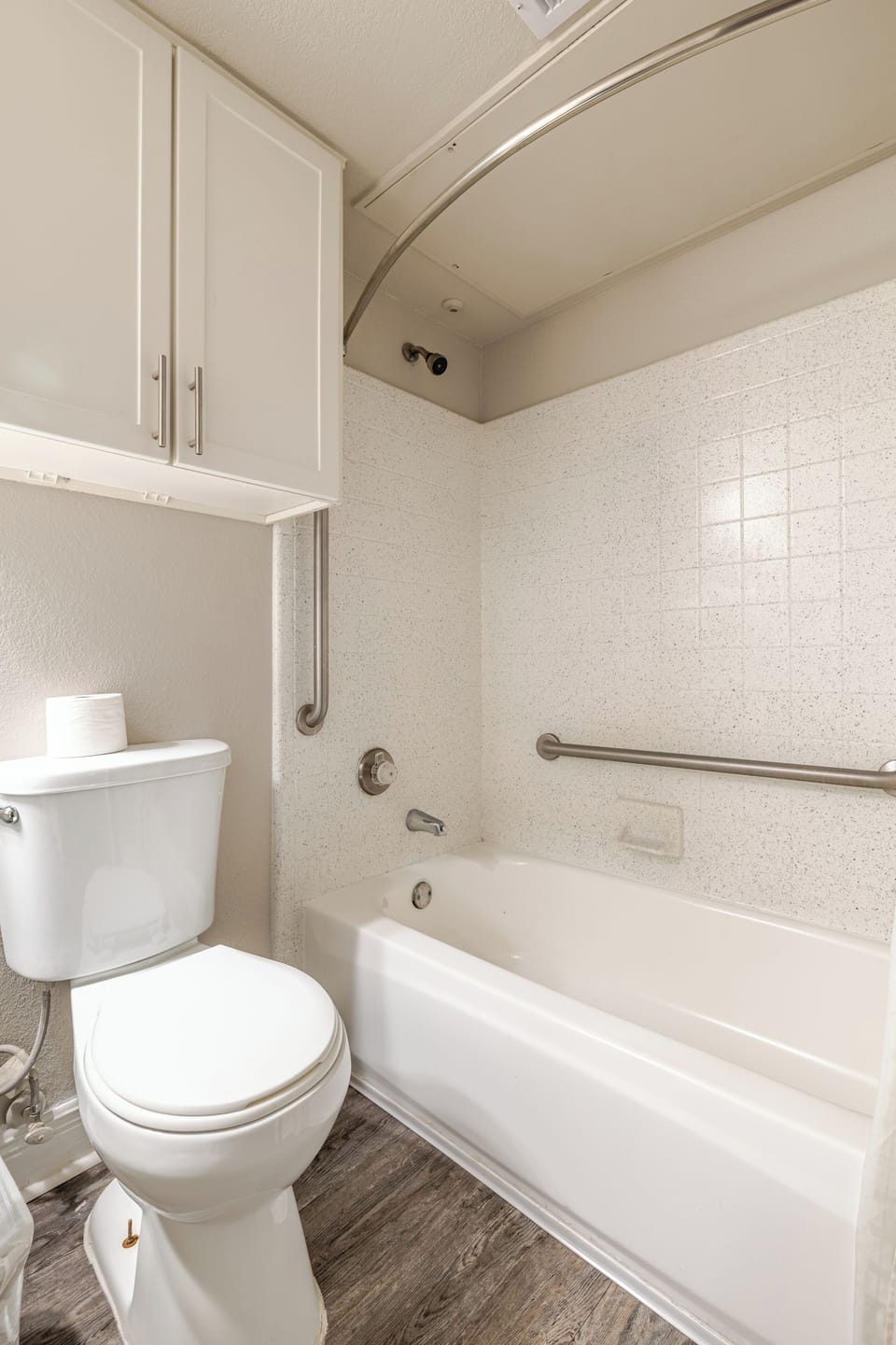 Bright bathroom with tub-shower combo, grab bars, and handy storage