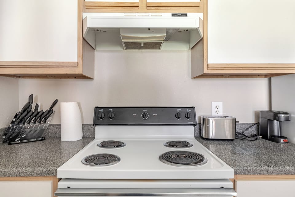 Bright kitchen with full stovetop, coffee maker, and meal prep essentials