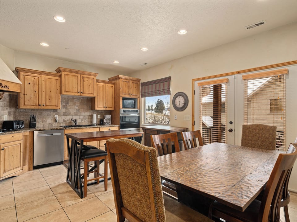 An open-concept kitchen with stainless steel appliances and warm finishes, seamlessly connecting to dining and living spaces for elevated everyday living.