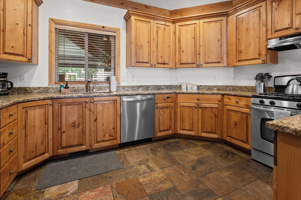 Fully equipped kitchen with granite countertops, stainless steel appliances, and convenient bar seating.