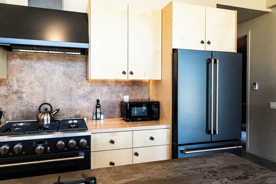 Modern kitchen with gas range, full-size fridge, and warm designer finishes