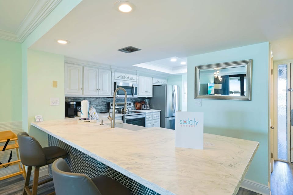 Gather around the spacious breakfast bar in this updated beachfront condo featuring quartz countertops, modern finishes, and a fully equipped kitchen.