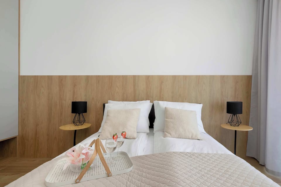 A closer view of the bed with neatly arranged pillows and a soft throw blanket. Wooden paneling behind the headboard and bedside lamps create a warm and inviting ambiance.