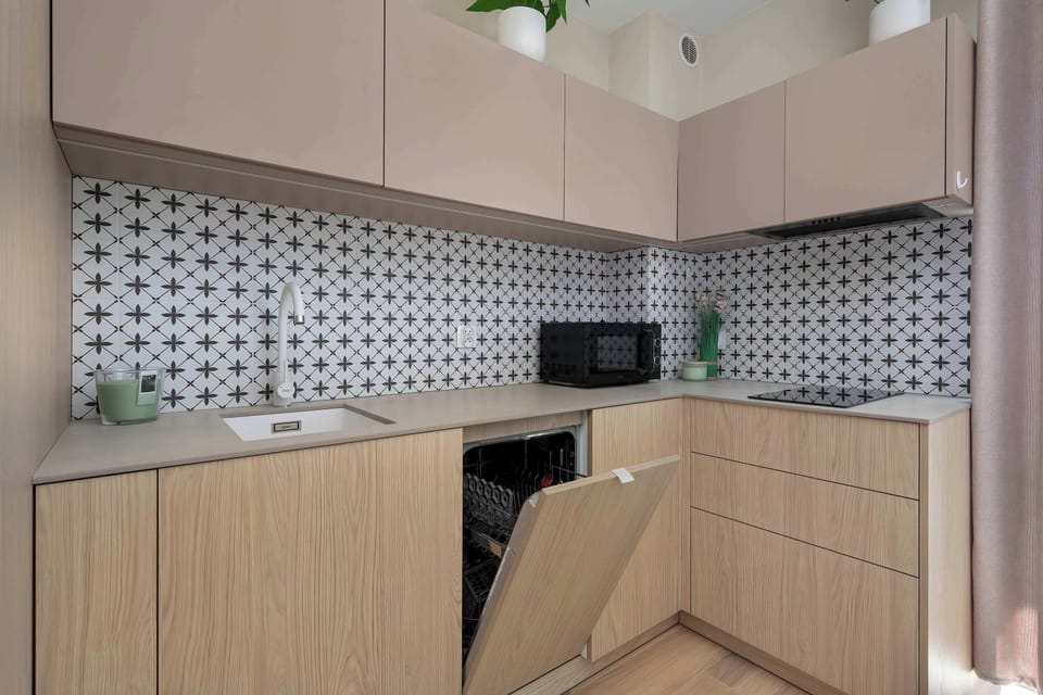 A small kitchen area with light cabinetry and a patterned backsplash detail.