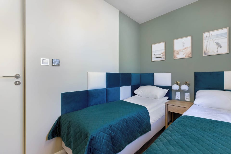 A second bedroom angle showing twin beds and light walls with minimal décor.