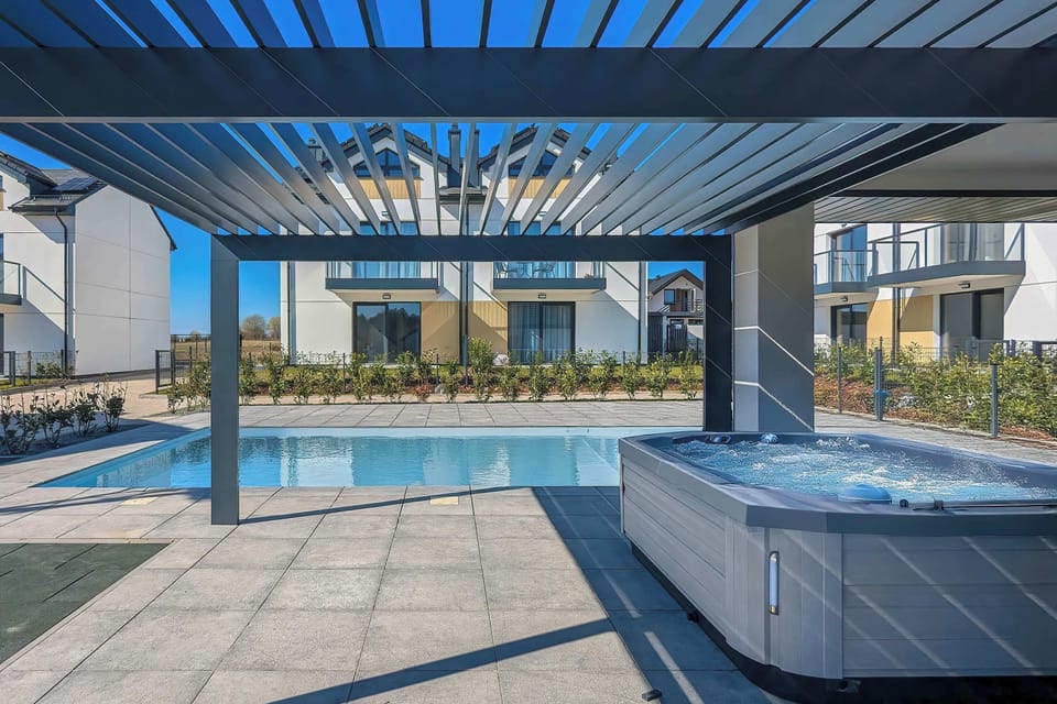 A terrace with a hot tub beneath a pergola, offering a relaxing outdoor setting.