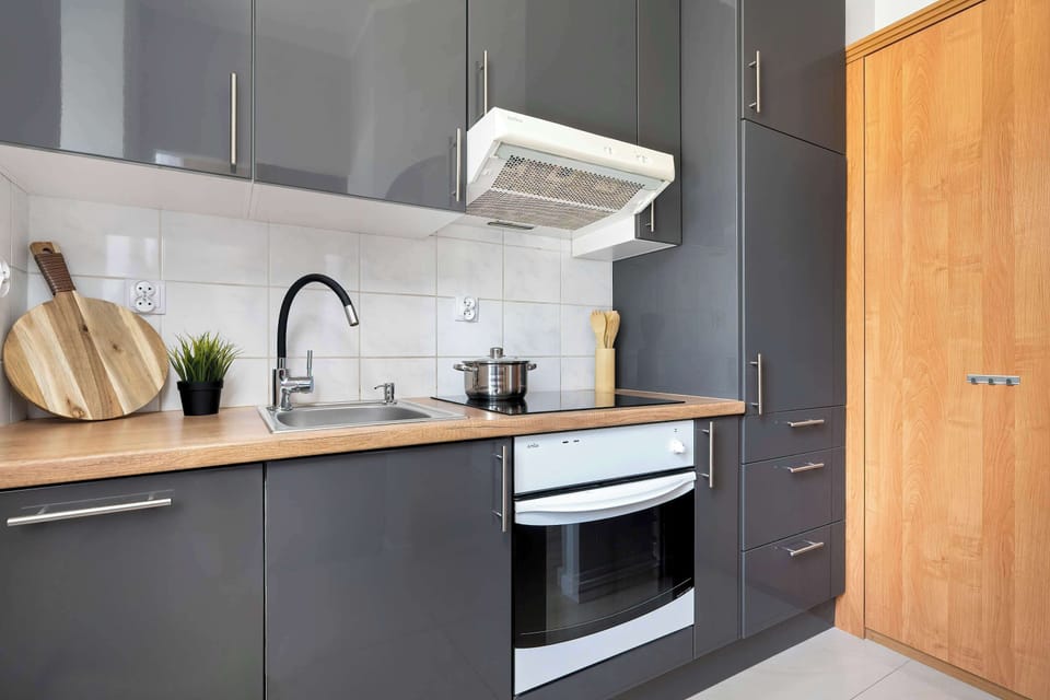 A compact kitchen with an oven, stove, and wooden countertop. It is well-organized and suitable for preparing meals easily.