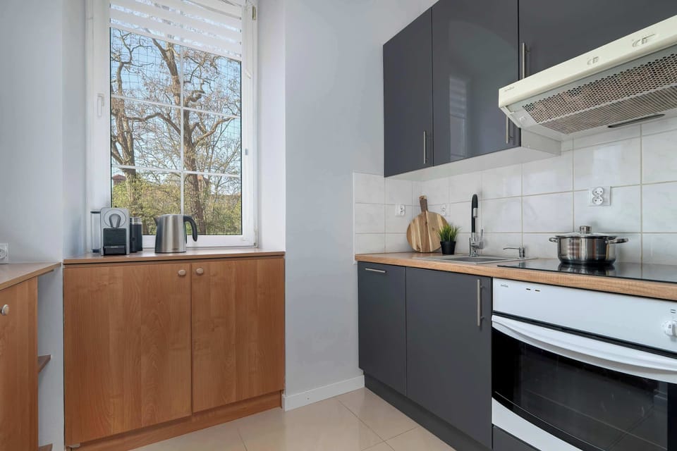 A kitchen area with cabinets, countertop, and natural light from a window. It offers a warm and functional cooking environment.