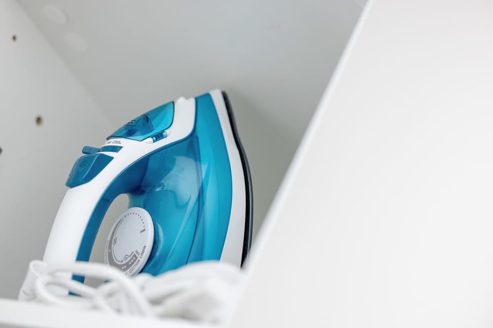 A white iron is stored neatly inside a cupboard, ensuring guests can keep their clothes pressed during their stay. This small detail highlights the apartment's full functionality.